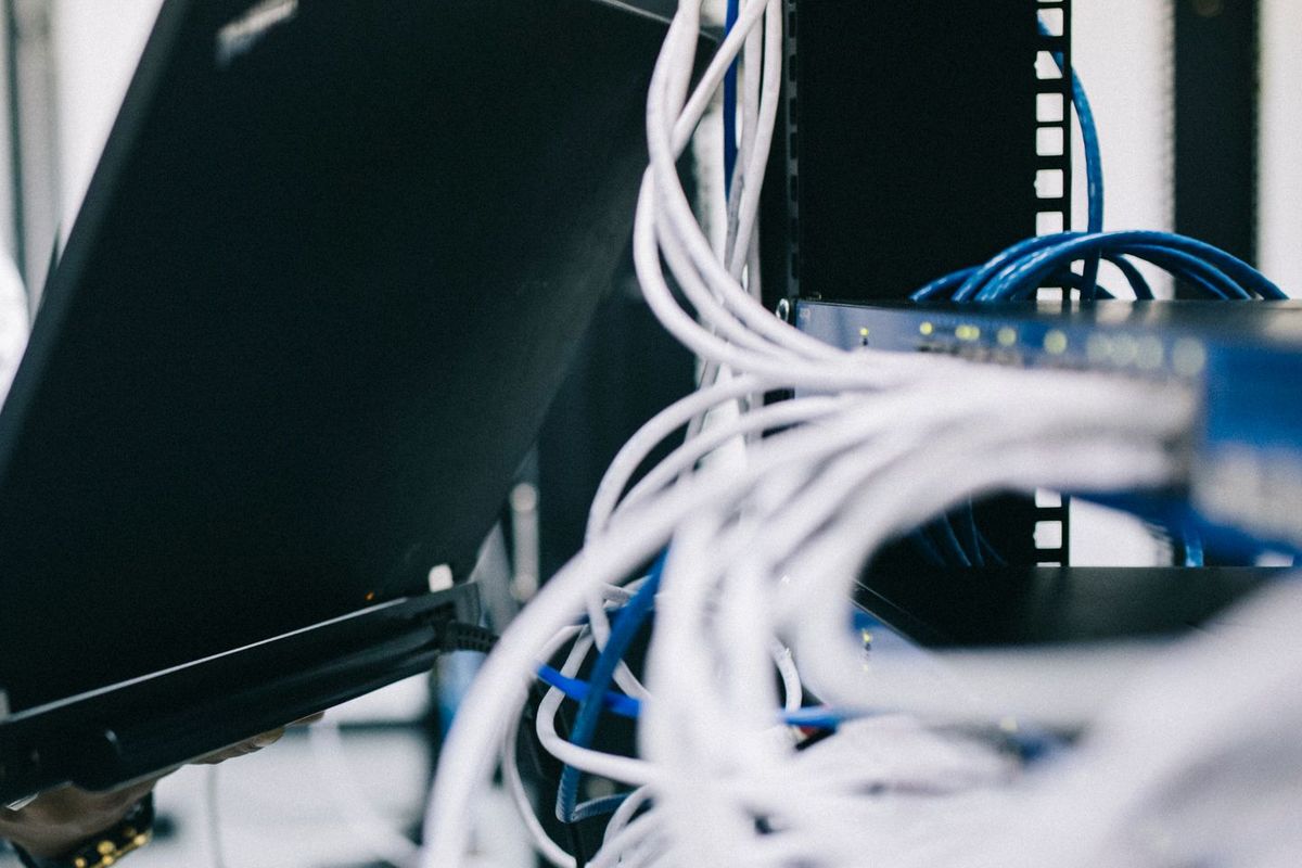 Technician with a laptop documenting equipment and cabling at a network rack